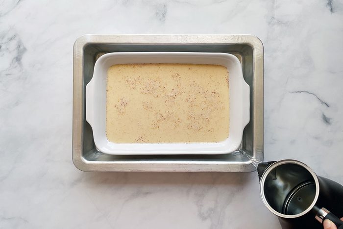 How to make Taste of Home's Baked Egg Custard, step 2 is pouring the custard mixture in a baking dish in a water bath
