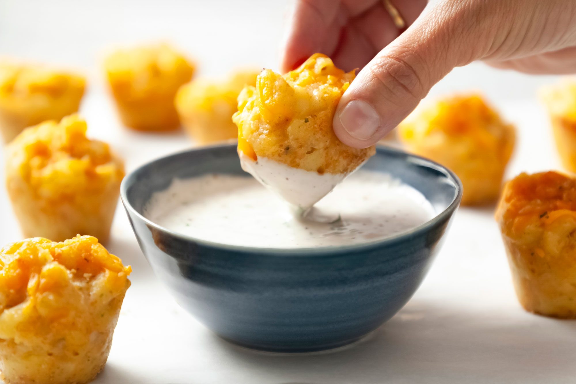 Table view shot of Mini Mac & Cheese Bites; served with dip bowl; on white paper sheet;