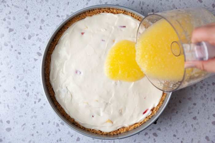 Step 4 of Taste of Home Mango Cheesecake is to make the gelatin topping in a food processor and then spread it over the cream cheese filling