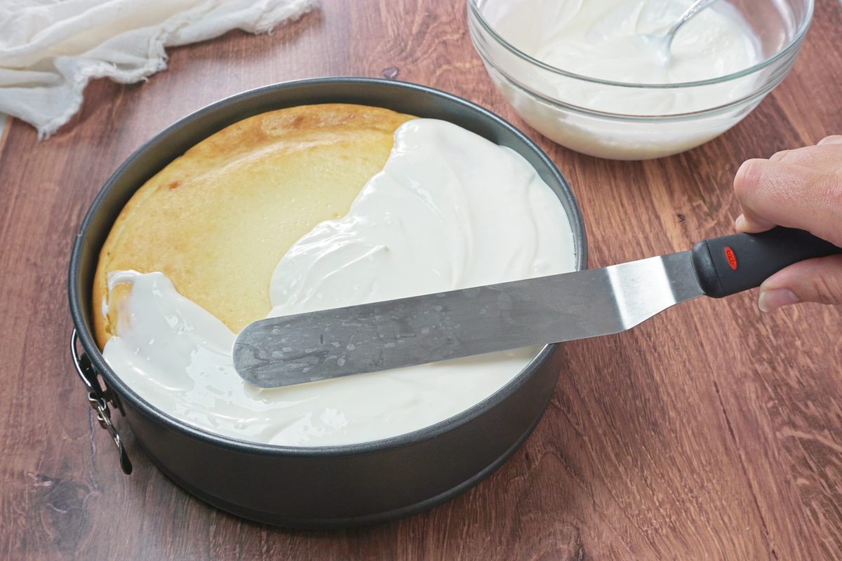 Spreading a sour cream topping onto an amaretto cheesecake RMS 91184 for Taste of Home