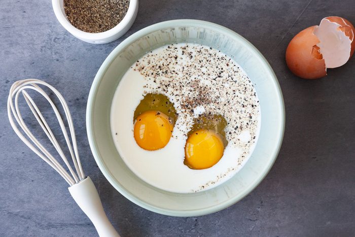 Step 2 of Taste of Home Bacon and Egg Muffins is to mix 2 of the eggs with the cream and pepper until combined