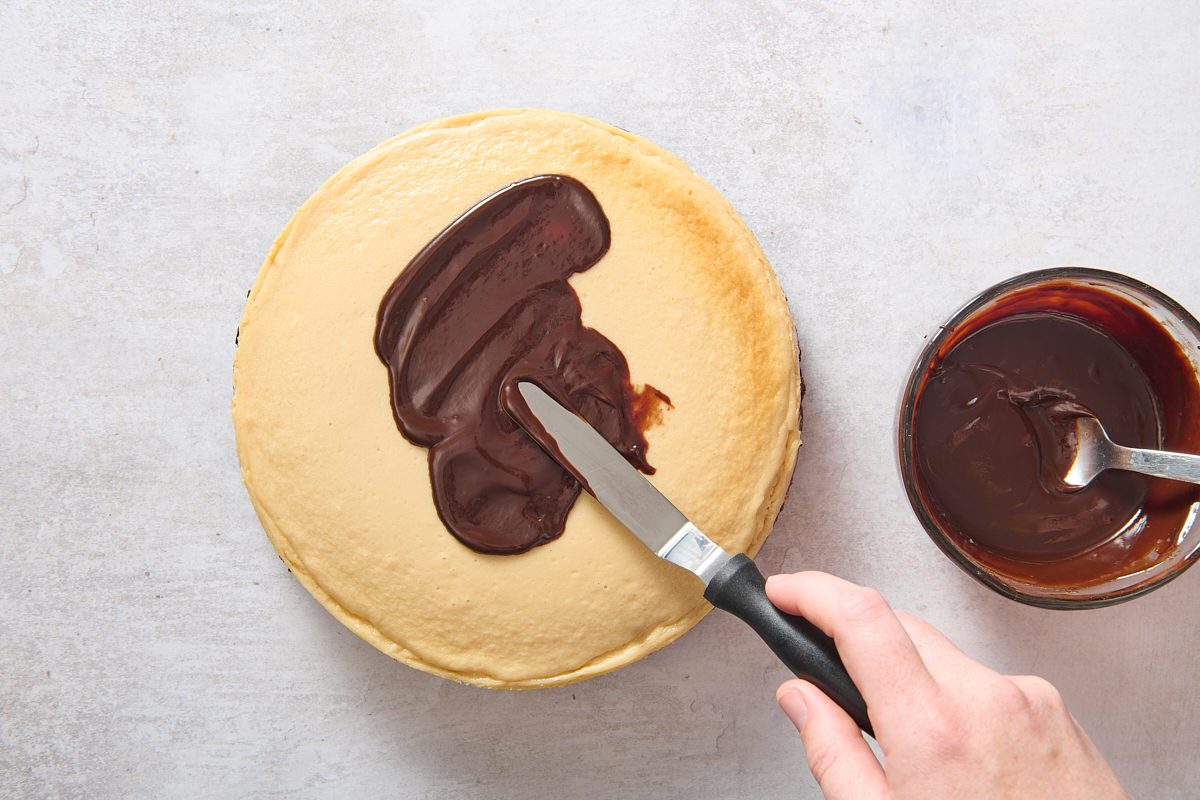 Spreading ganache over the cooled cheesecake
