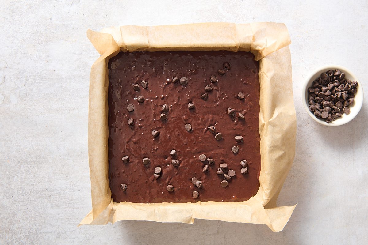 Sprinkling chocolate chips over the batter in a square baking pan