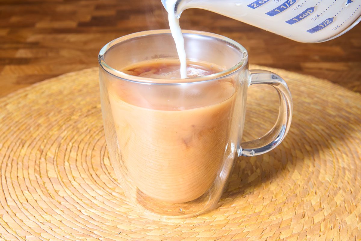 Warm milk being poured into mug of tea