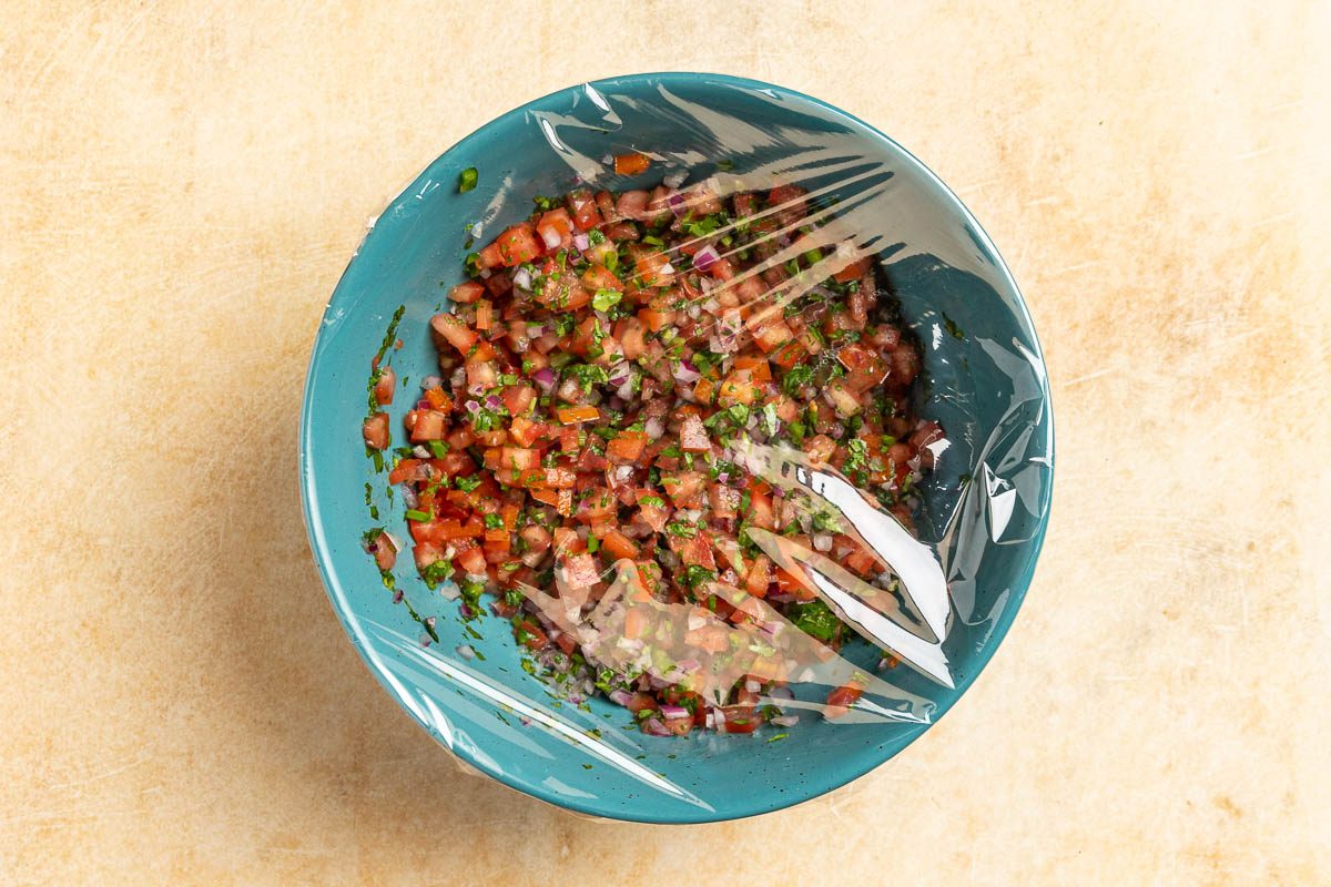 Taste of Home Copycat Chipotle Pico de Gallo recipe photo of the bowl covered in plastic wrap for refrigeration.