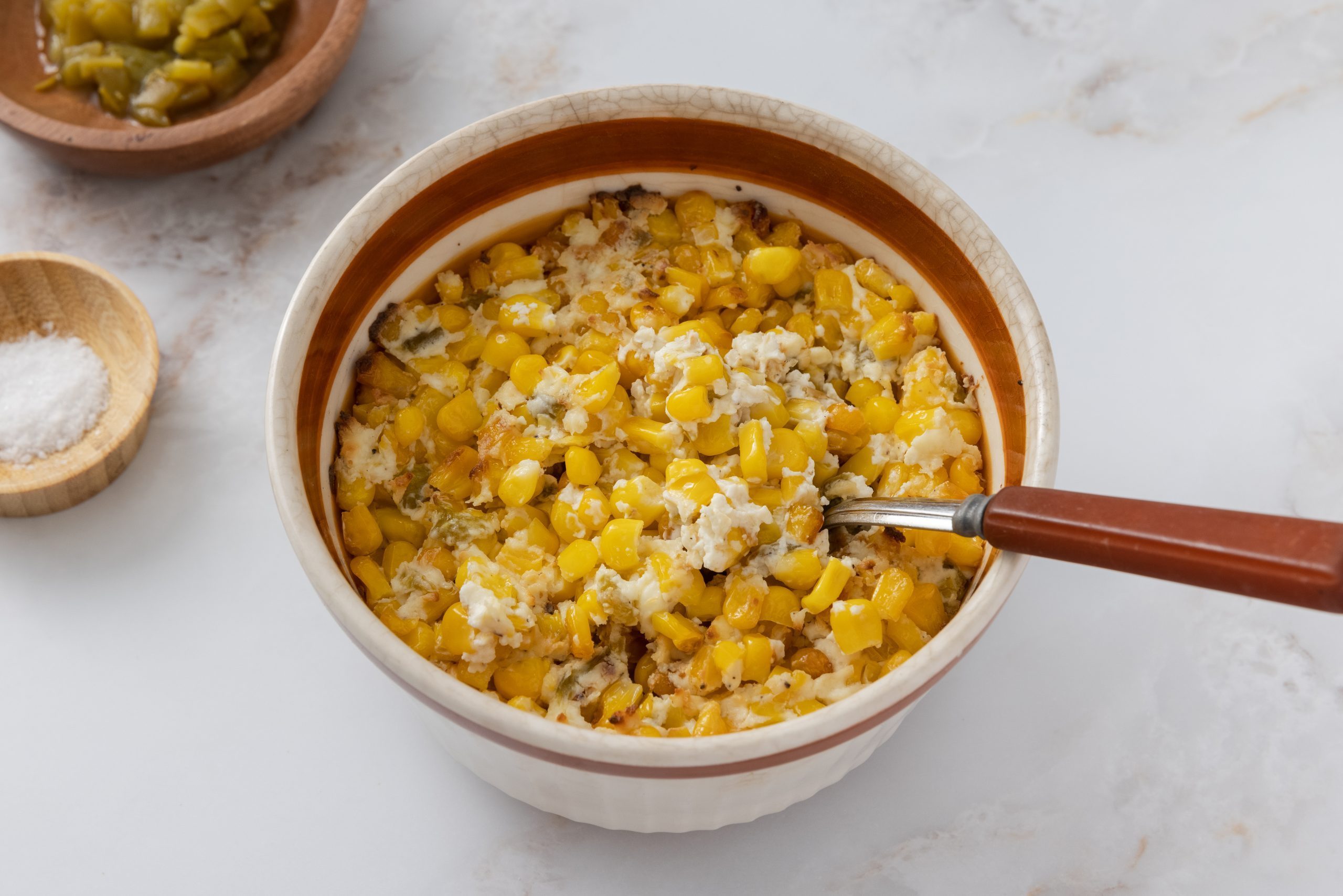 Corn casserole with cream cheese served in baking dish.
