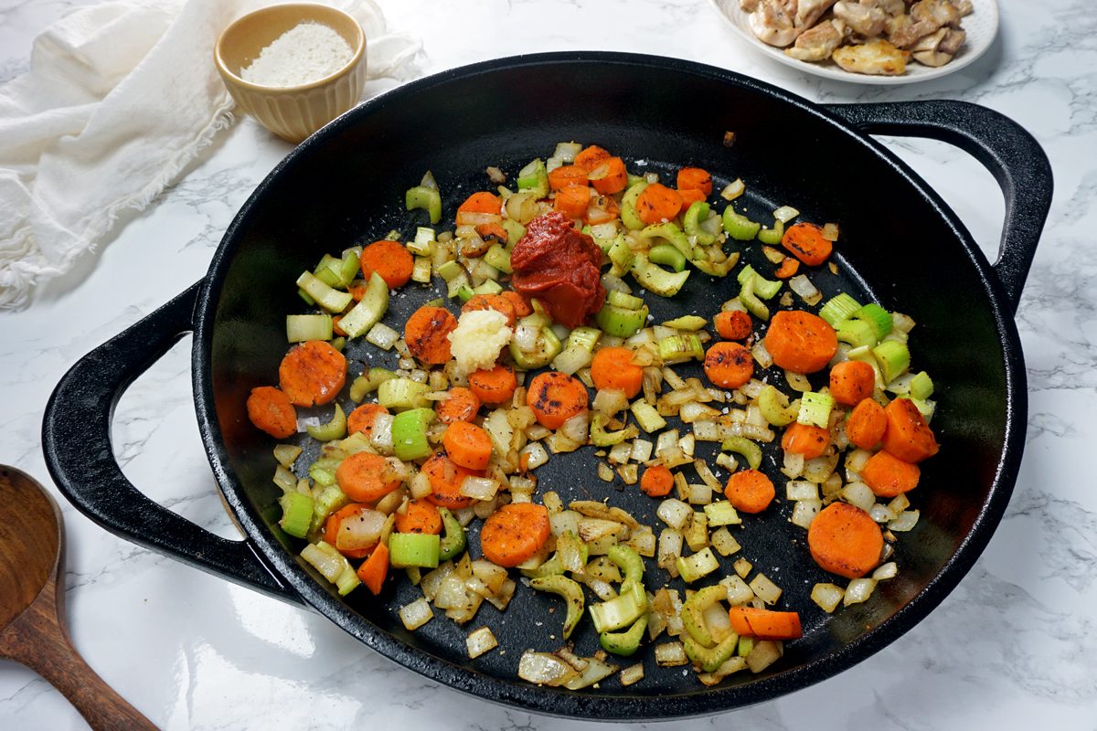 A skillet with carrots, celery and tomato paste to make Crock-Pot Chicken and Dumplings RMS 201122 for Taste of Home