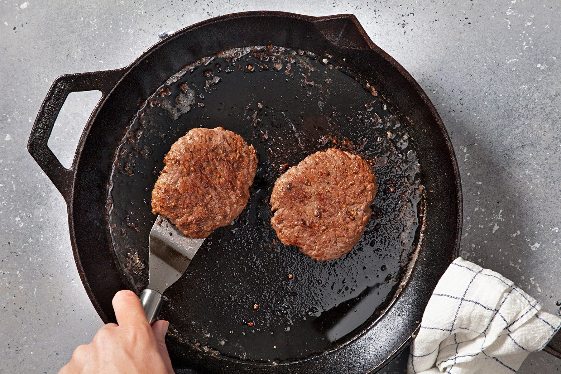 overhead shot; greu textured background; In the skillet, cookinh patties