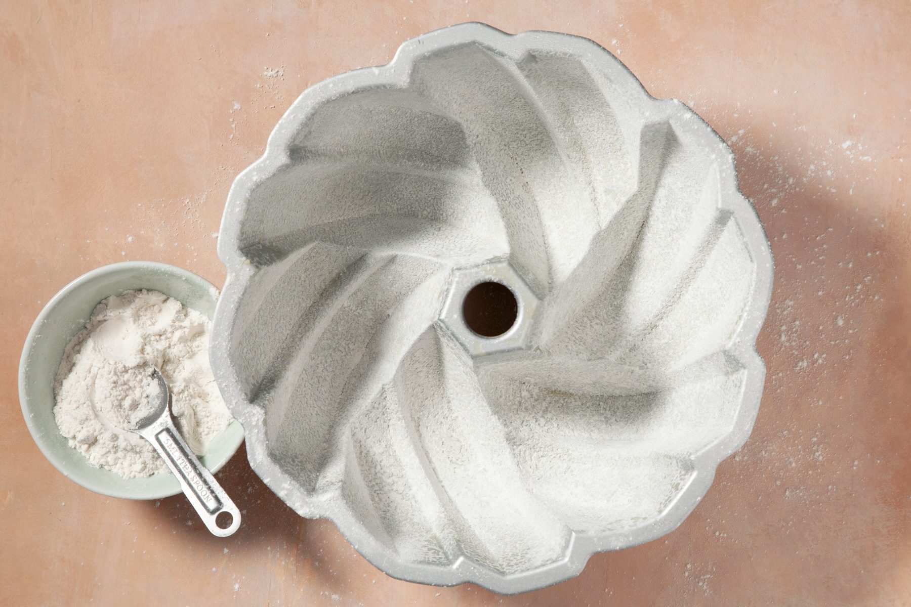 Top view of greasing and flouring a fluted tube pan