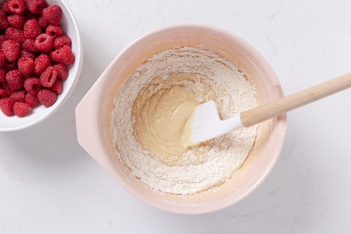 Muffins dough being mixed in before adding fresh raspberries.