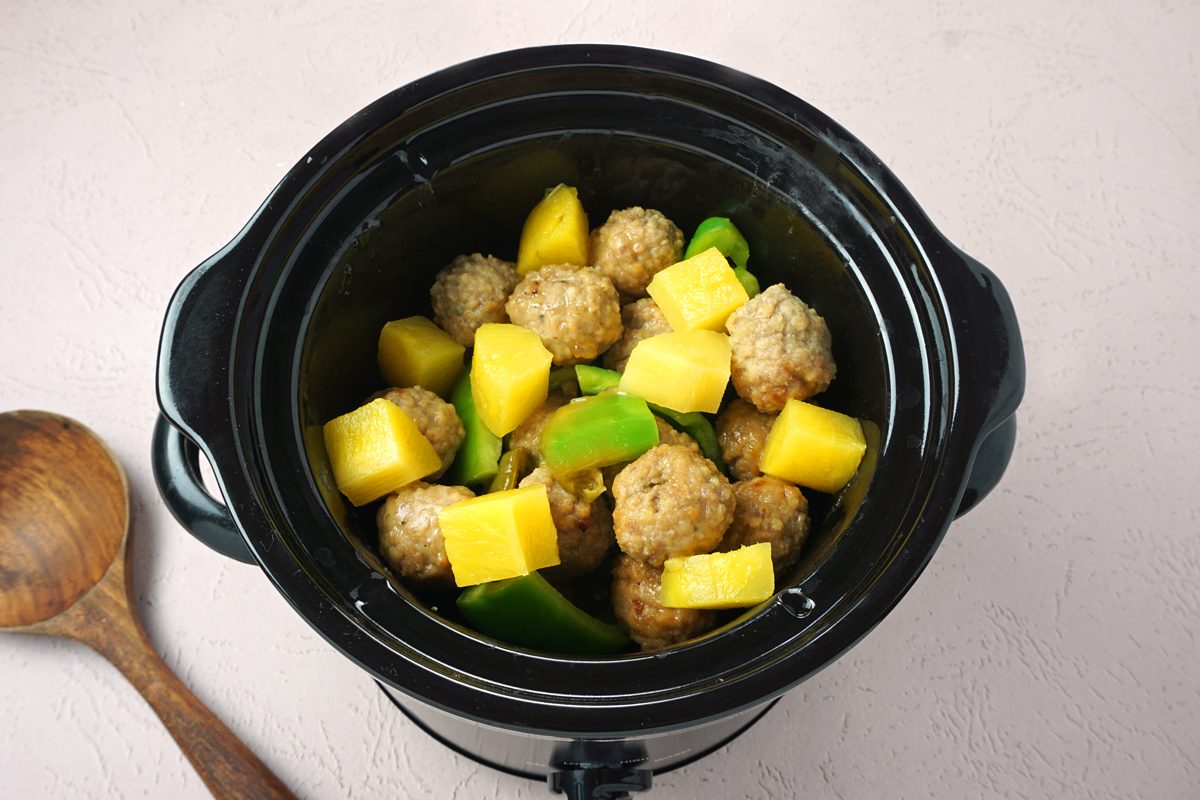 A crockpot with pineapple, green peppers, ad meatballs to make slow cooker sweet and sour meatballs for Taste of Home RMS 27421