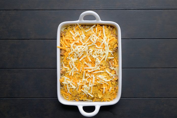 overhead shot; black background; In an baking dish, layered half of the meat mixture with chips and cheeses.