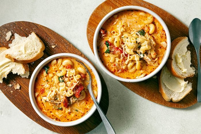 wide shot of creamy tuscan chicken soup with shredded cheese