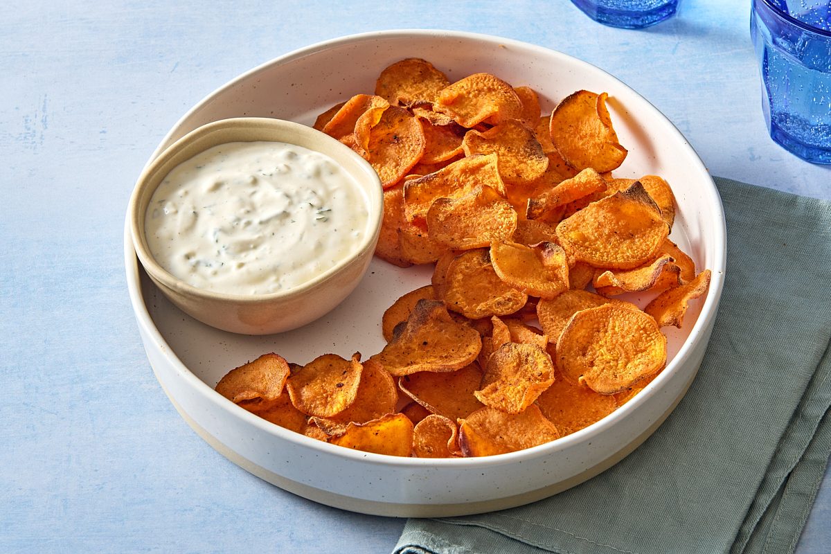 Angled shot of a platter of air fryer sweet potato chips with a small bowl of dipping sauce