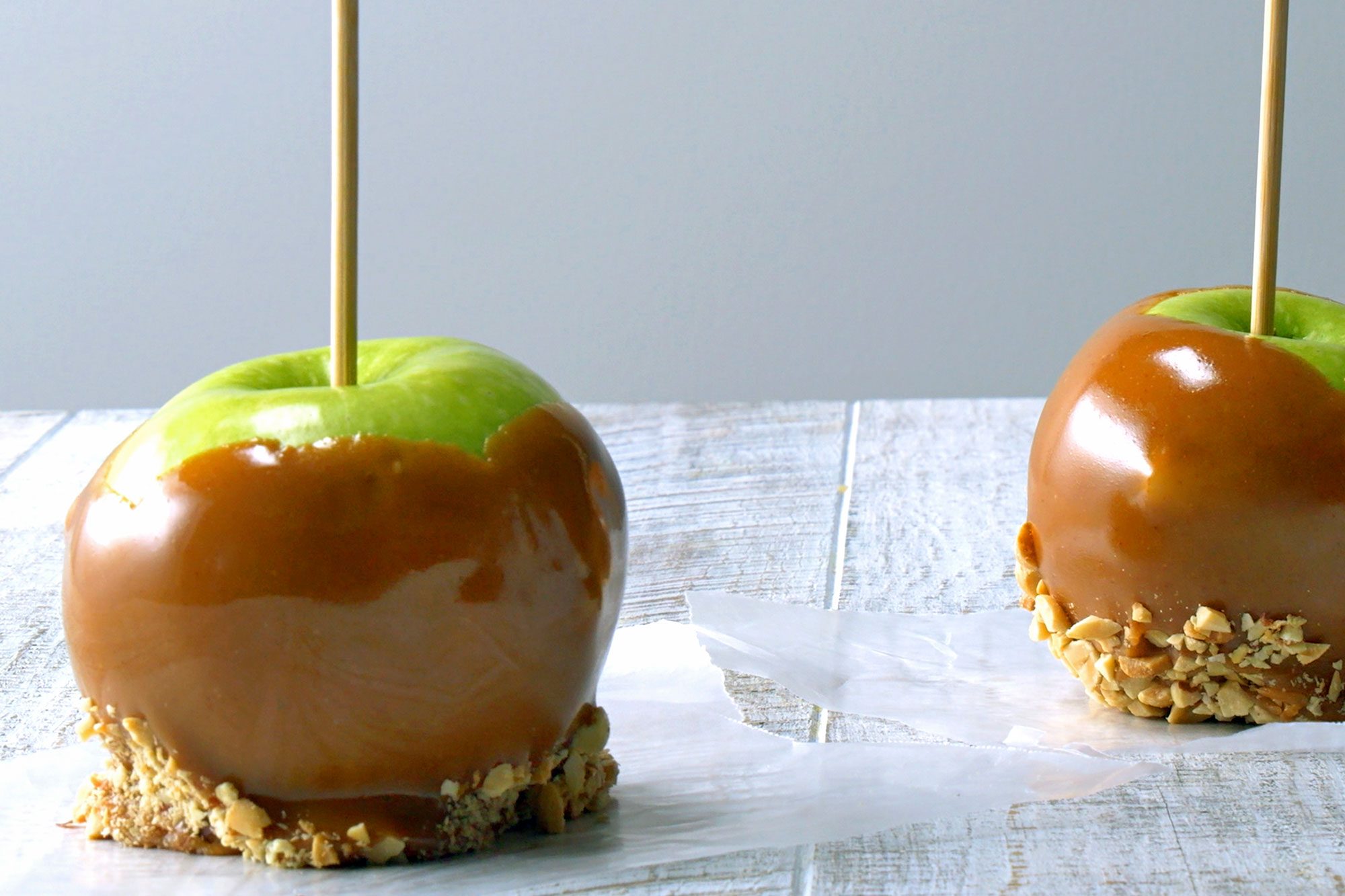 Two Caramel Apples placed on wooden table to set