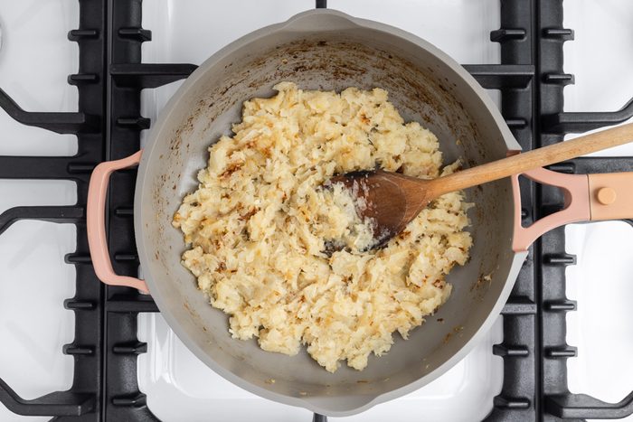 Onions being cooked in skillet.