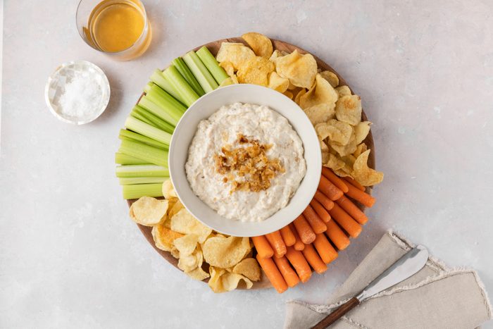 Caramelized onion dip served with fresh vegetables and potato chips.