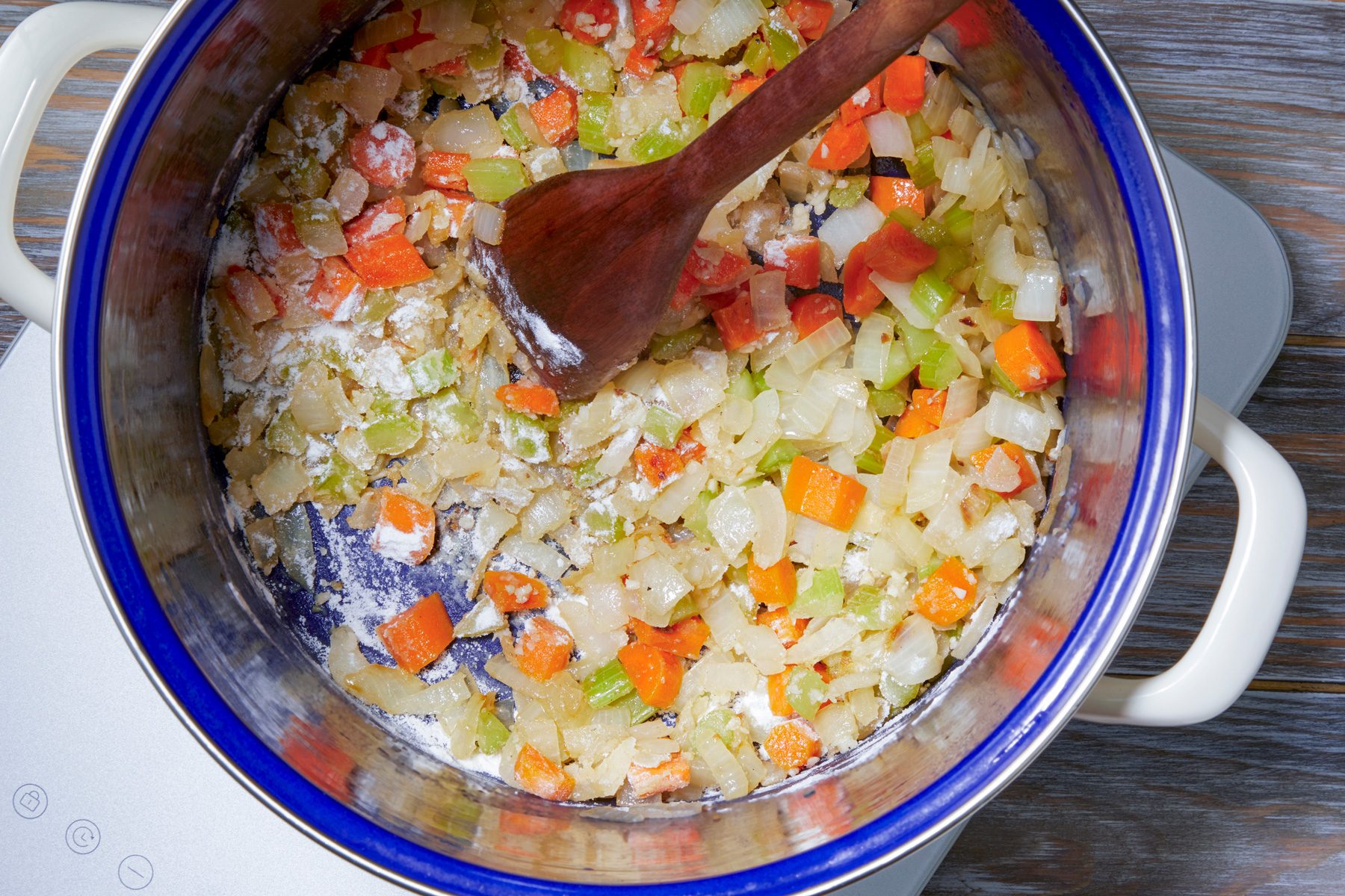 overhead shot; wooden background; Stiring flour and vegetables using a wooden spatula until Blended