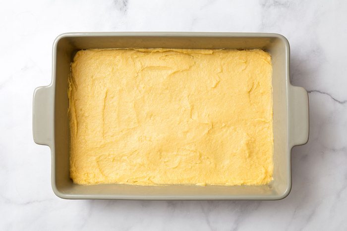 Dough in 9 by 13 baking dish for step two of Cream Puff Cake recipe for Taste of Home