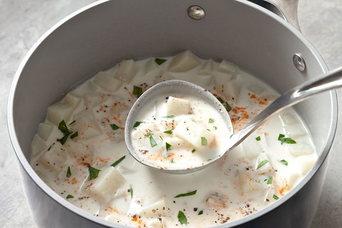 Cream of Potato Soup in a large saucepan; close view of Cream of Potato Soup in serving spoon