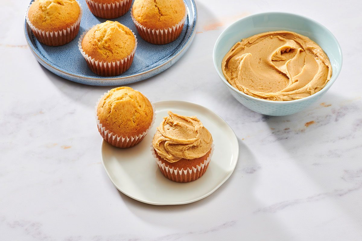 Caramel vanilla frosting spread on a muffin, with a bowl of frosting nearby