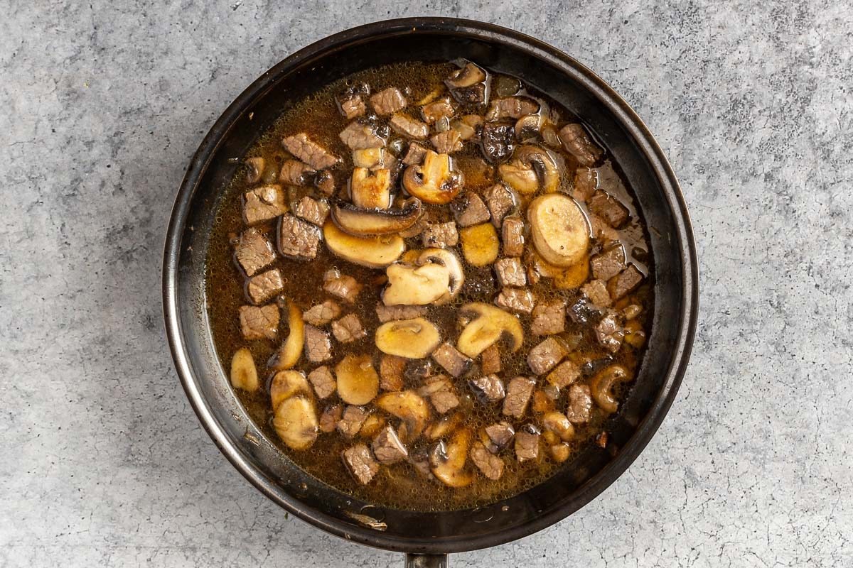 Taste of Home Easy Beef and Noodle recipe photo of the sauteed onion and mushroom, beef, and broth in a skillet.