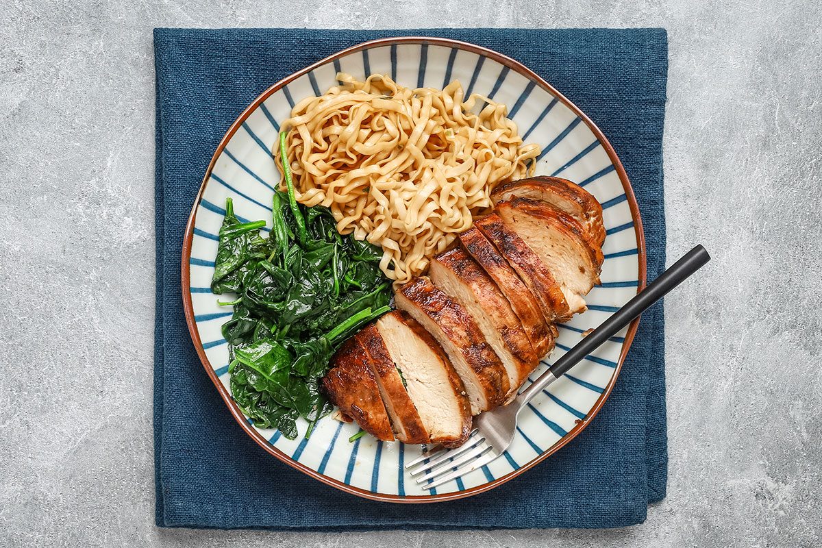 Grilled teriyaki chicken breasts on a plate with noodles and spinach, from a Taste of Home recipe.