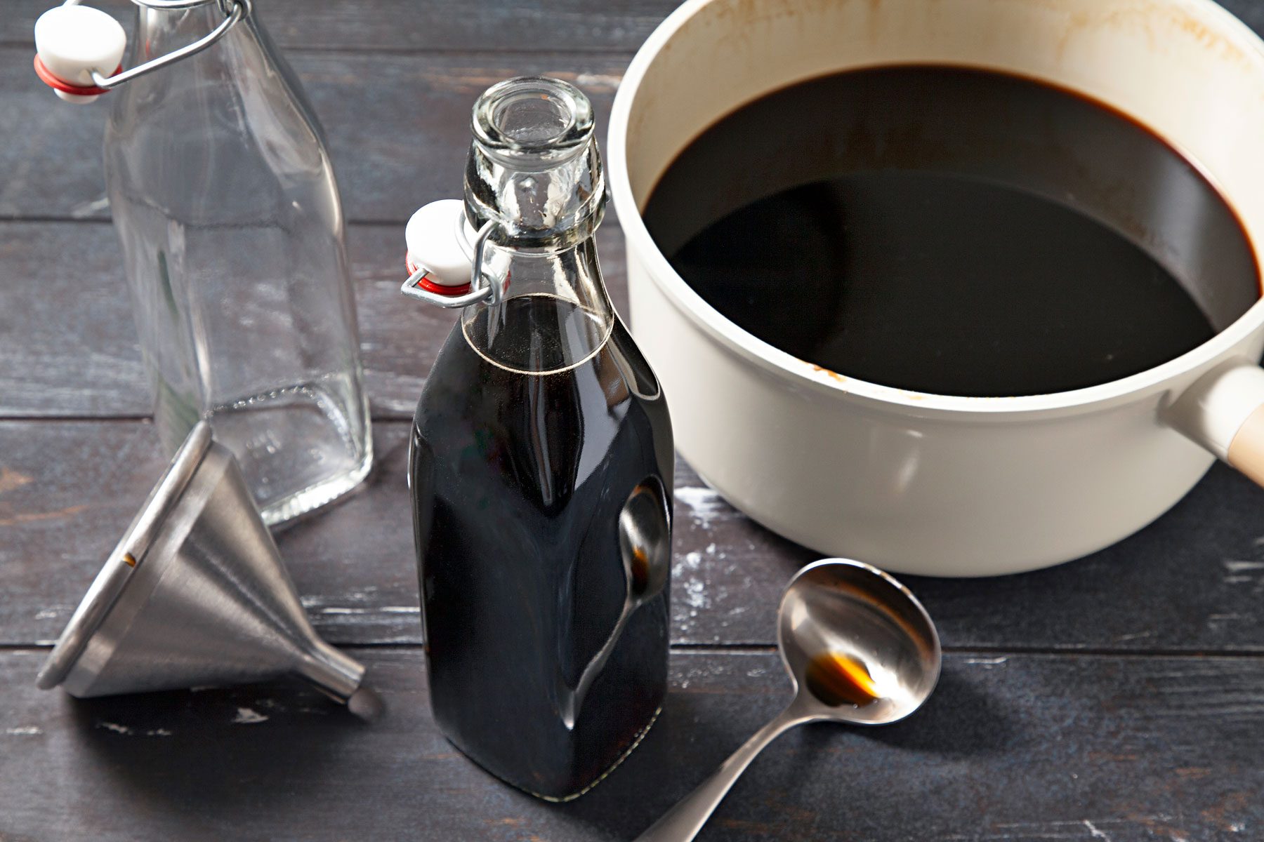 Kahlua stored in a glass bottle with a large saucepan next to it containing remainder.