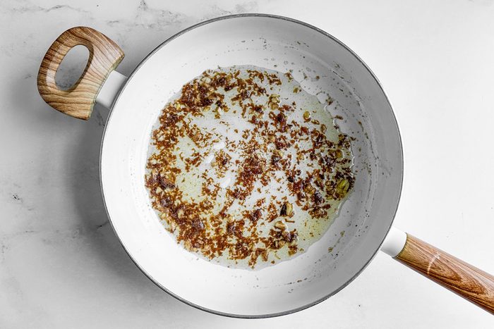 Anchovies and olive oil for Taste of Home Linguine with Clam Sauce in a white skillet on a marble surface
