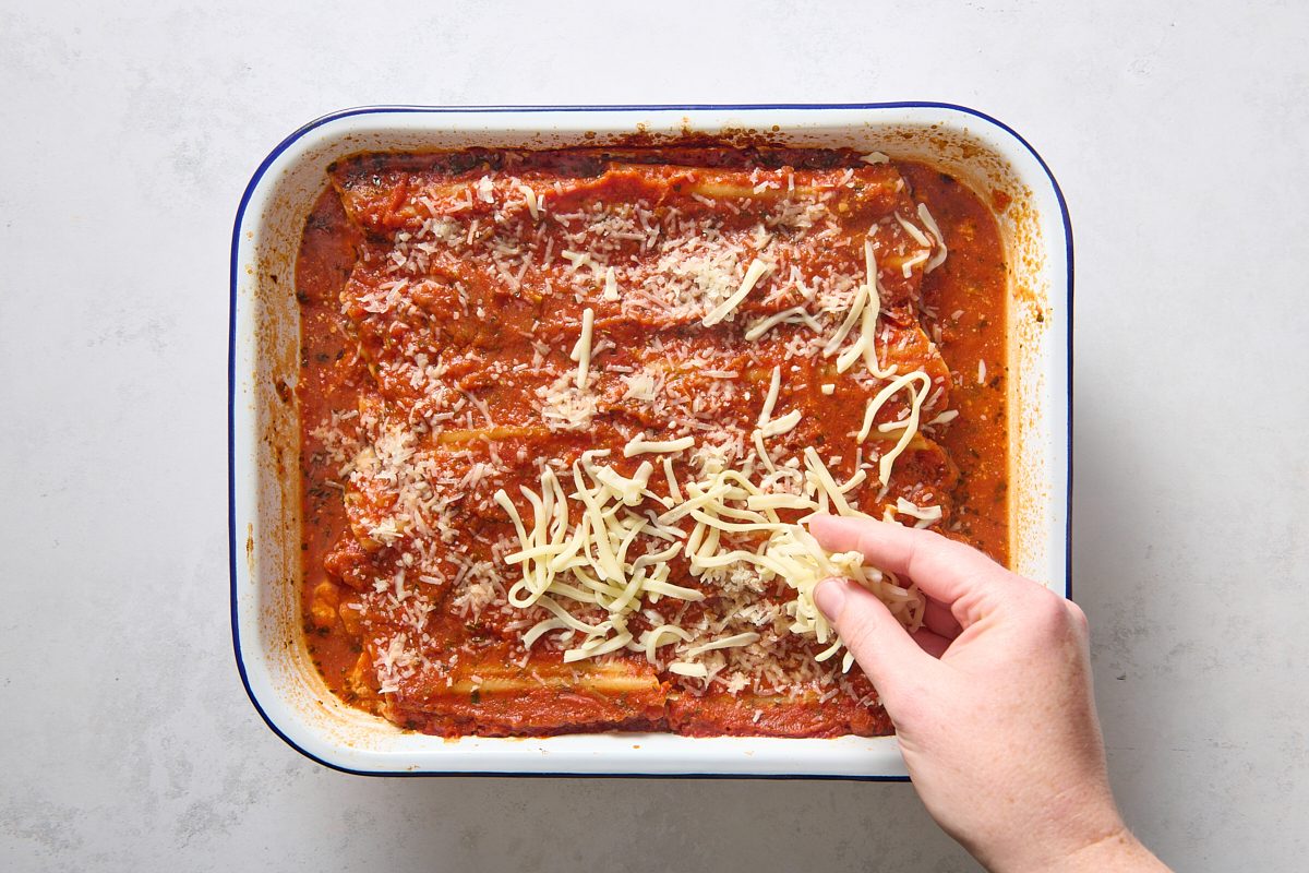 Sprinkling cheese over the baked manicotti