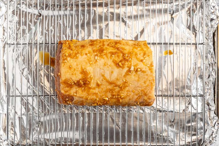 Taste of Home Marinated Pork Loin photo of the marinated pork loin on a greased rack over a foil lined roasting pan.