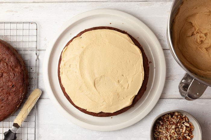 Step 4 of Taste of Home Jam Cake is to In a large saucepan, melt the butter for the icing over medium heat. Stir in the brown sugar and the milk, and bring the mixture to a boil (the sugar should dissolve completely). Remove the saucepan from the heat and cool it until the mixture is just warm. Beat in the confectioners' sugar gradually until the icing reaches a spreadable consistency. Spread the frosting between the layers, and then over the top and sides of the assembled cake. For a more finished appearance, press additional chopped pecans to the sides of the cake and then decorate the top with pecan halves.