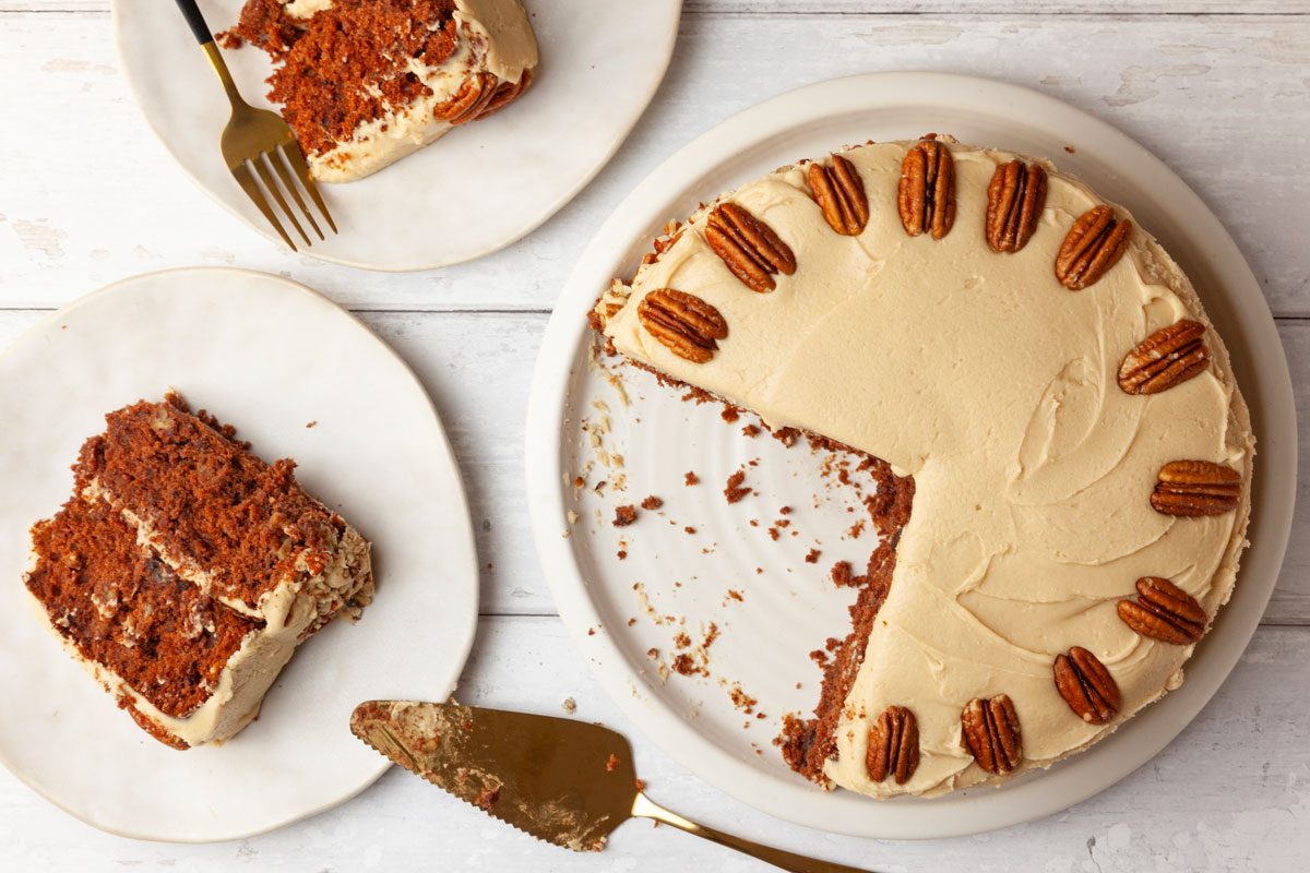 Full yield of Taste of Home Jam Cake on white wood surface, single servings peaking in, gold pie cake server