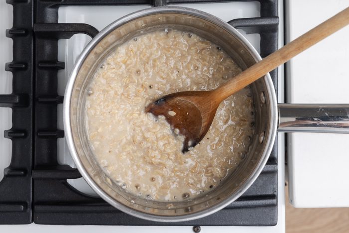 Oats being cooked with water and salt on stovetop.