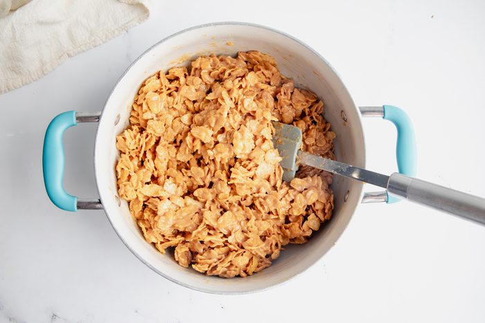 Overhead shot for Taste of Home Peanut Butter Cornflake Cookies with cornflakes and peanut butter mixture being tossed together.