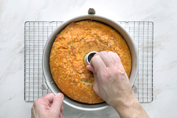 Removing baked cake from the pan placed over wired rack