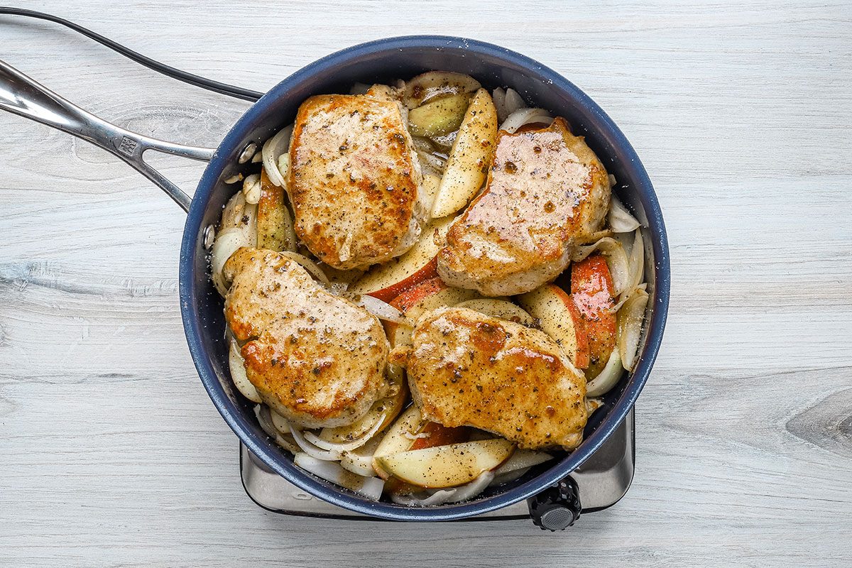 Simmering boneless pork chops with apples and sliced onion for a skillet recipe from Taste of Home.