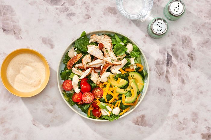 Chicken taco salad assembled on a serving plate with extra salad dressing on the side