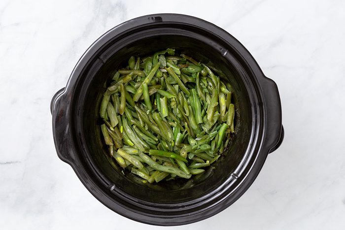 Cooked green beans in a slow cooker for step three for Slow Cooker Green Beans recipe for Taste of Home