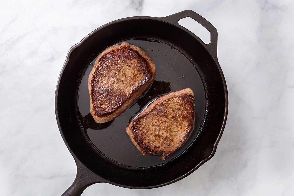 Top sirloin steaks being seared in a large skillet for step two for Steak Pizzaiola recipe for Taste of Home