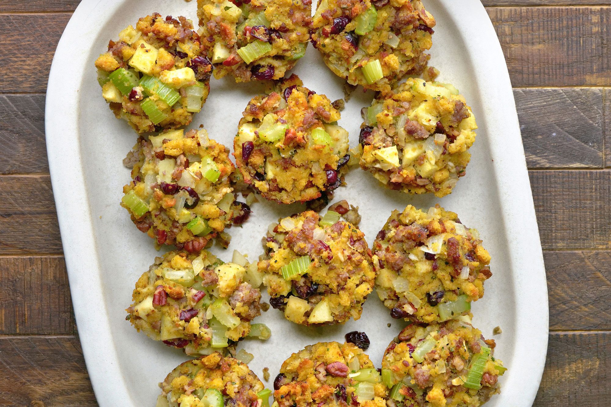 overhead shot of sausage stuffing muffins in a white dish; Wooden Background;