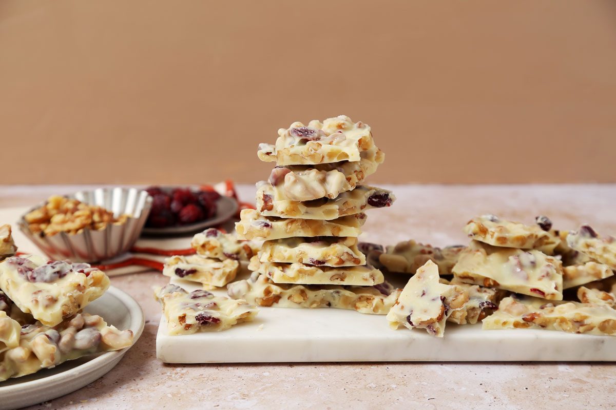 Close up of Taste of Home's White Chocolate Bark served on a white plate on a beige countertop.