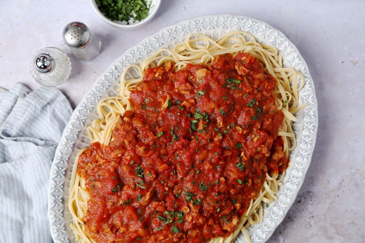 Close up of Taste of Home's Red Clam Sauce served on top of cooked linguine on a blue platter.