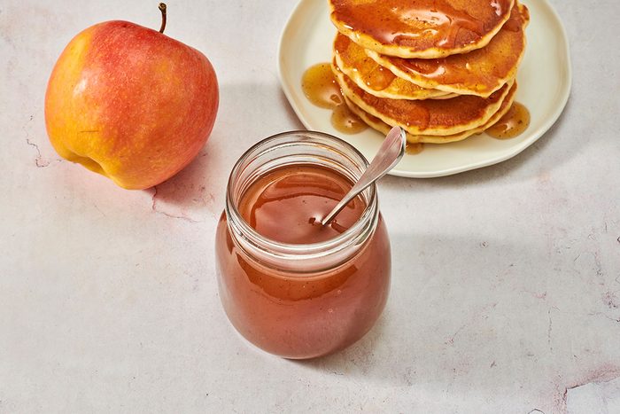 Syrup in a jar with a stack of pancakes in the background