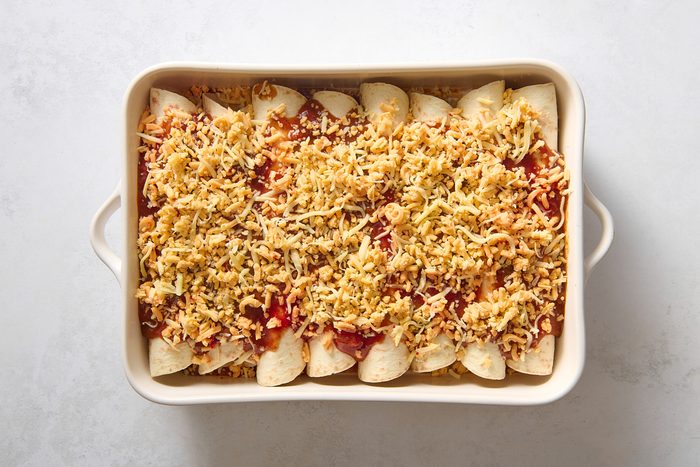 Breakfast enchiladas sprinkled with cheese before baking