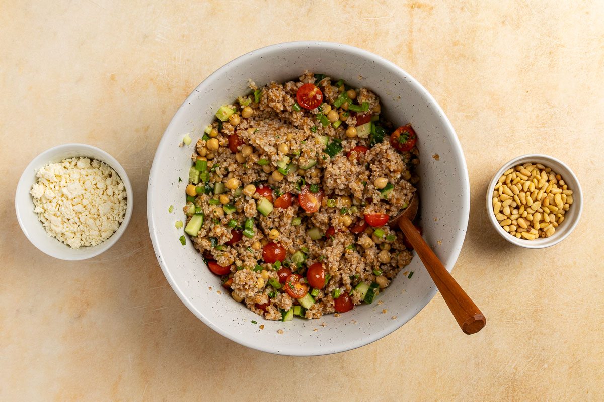 assembled salad with pine nuts and feta cheese toppings on the side.