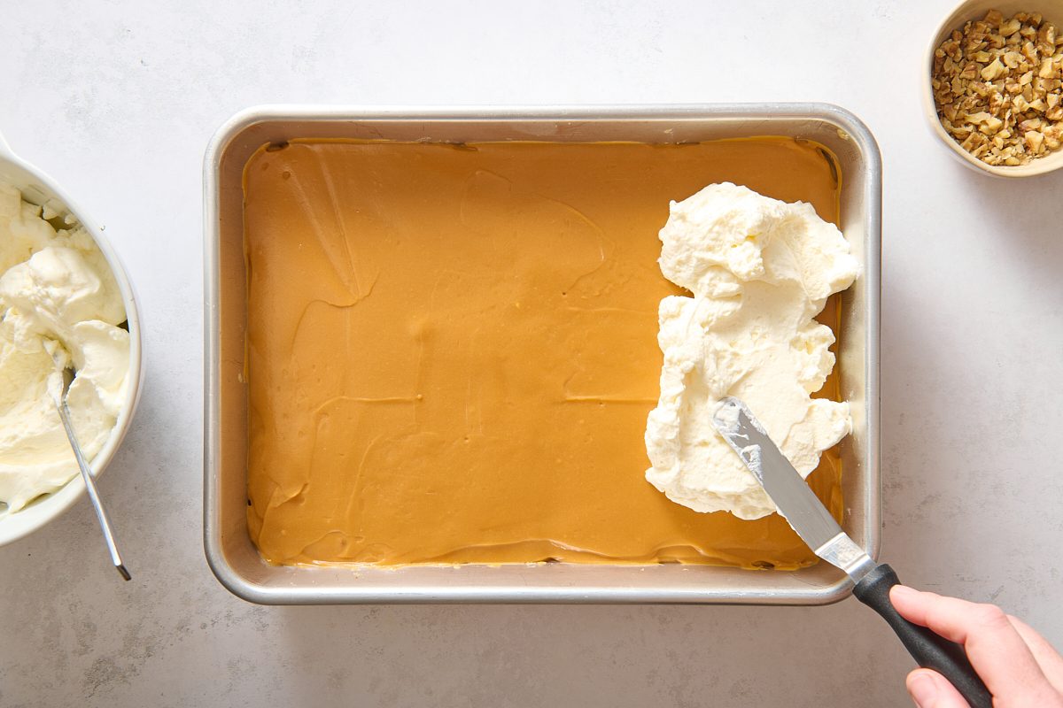 Spreading whipped topping onto the layered dessert