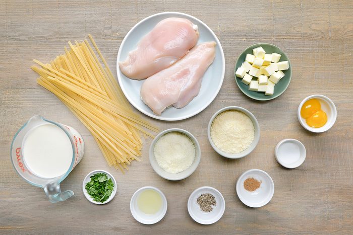 overhead shot of Chicken Alfredo ingredients placed over wooden background;