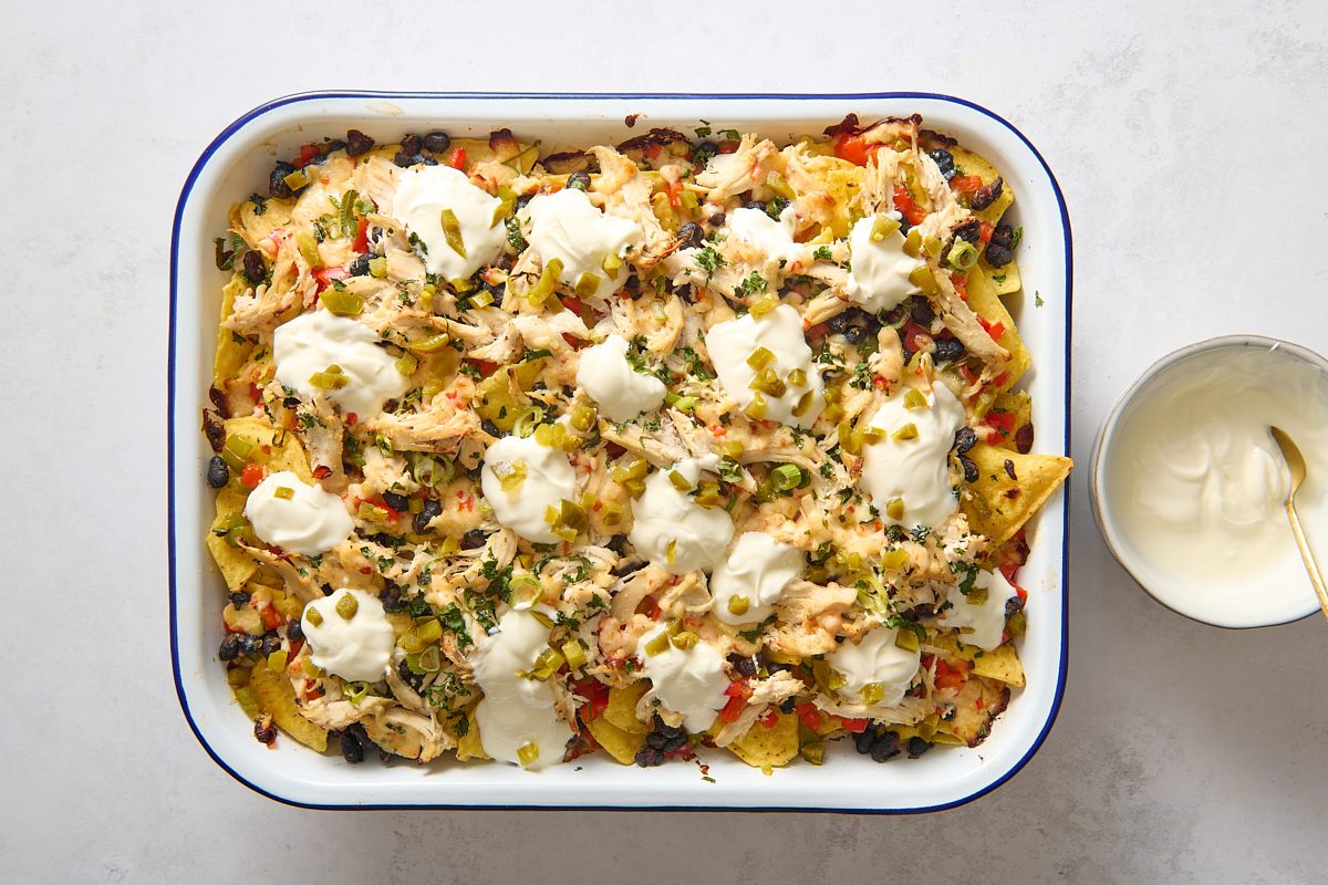 Chicken nachos after baking, topped with sour cream and jalapenos