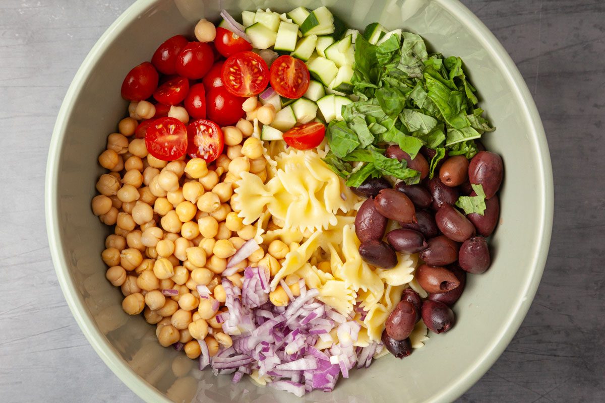 Step 2 of Taste of Home Chickpea Pasta Salad is to Stir in the chickpeas, tomatoes, cucumber, onion, olives and basil.